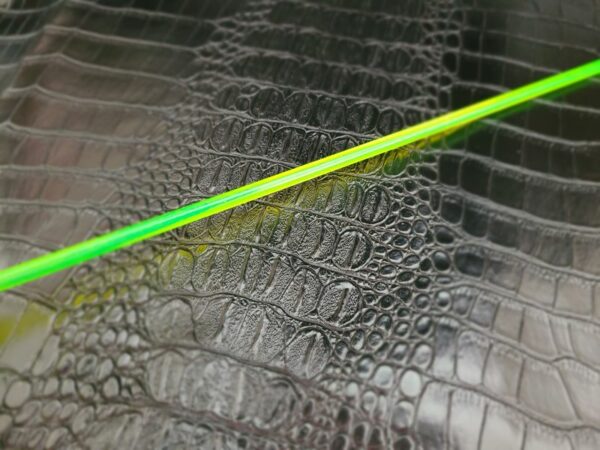 Neon green acrylic rod against alligator faux leather
