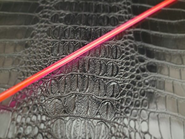 Neon pink/red acrylic rod against alligator faux leather